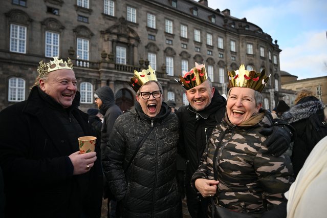 People wearing makeshift crowns and warm clothes wave react in the early morning at Christiansborg Palace Square as they wait for the proclamation of abdication of Denmark's Queen Margrethe II, in Copenhagen, Denmark, on January 14, 2024. Denmark turns a page in its history on January 14 when Queen Margrethe abdicates and her son becomes King Frederik X, with more than 100,000 Danes expected to turn out for the unprecedented event. (Photo by Jonathan Nackstrand/AFP Photo)