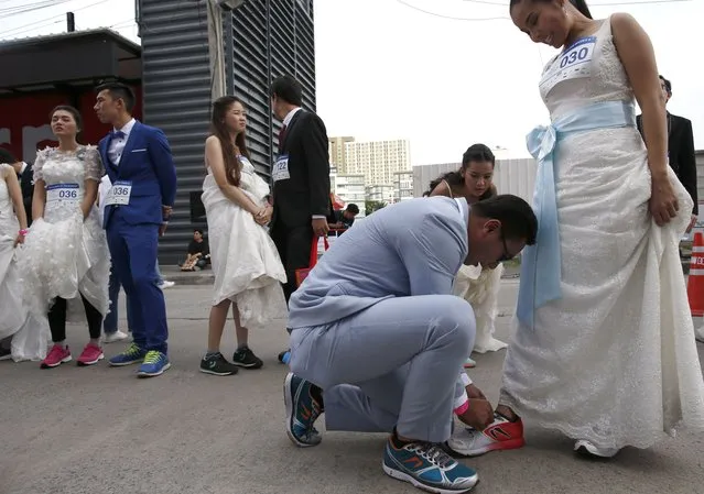 A Thai groom-to-be does up his bride-to-be shoelaces before competing in the “Running of the Brides” event in Bangkok, Thailand, 02 December 2017. (Photo by Rungroj Yongrit/EPA/EFE/Rex Features/Shutterstock)