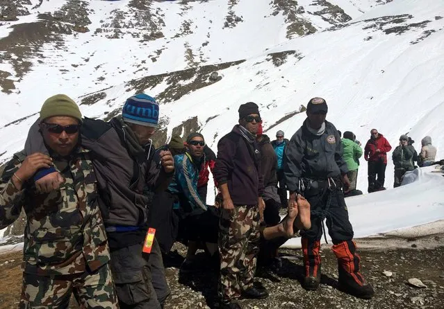 A handout picture made available by the Nepalese Army shows members of the army rescue unidentified trekkers from the Thorung La mountain pass on the Annapurna Circuit, near Muktinath, in Mustang district, Nepal, 17 October 2014. (Photo by EPA/Nepalese Army)