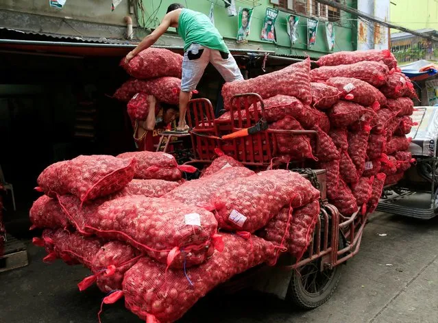 A worker helps his colleague carry sacks of red onions which they deliver to a warehouse in Metro Manila, Philippines July 4, 2016. (Photo by Romeo Ranoco/Reuters)