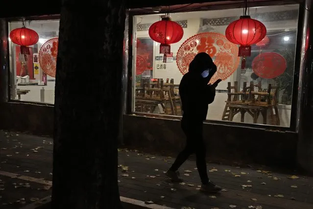 A woman wearing a mask walks past a restaurant closed to dine-in customers in Beijing, Tuesday, November 22, 2022. More than 253,000 coronavirus cases have been found in China in the past three weeks and the daily average is rising, the government said Tuesday, adding to pressure on officials who are trying to reduce economic damage by easing controls that confine millions of people to their homes. (Photo by Ng Han Guan/AP Photo)