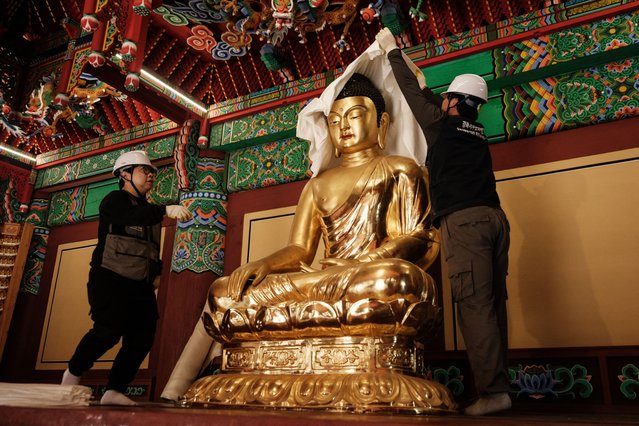 Members of the Gyeongbuk Seobu Cultural Heritage Care Center wrap a Buddha statue with cotton cloth and a fire-retardant blanket after evacuating all other items the night before, during preparations for the possibility of a wildfire advancing towards Gounsa Temple in Uiseong on March 25, 2025. Deadly wildfires in South Korea worsened overnight, officials said on March 25, as dry, windy weather hampers efforts to contain one of the country's worst-ever fire outbreaks. (Photo by Yasuyoshi Chiba/AFP Photo)