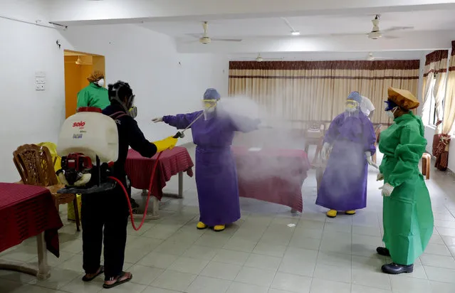 Sri Lankan municipal health workers are disinfected after a swab sample collecting session to test for COVID-19 in Colombo, Sri Lanka, Tuesday, July 14, 2020. (Photo by Eranga Jayawardena/AP Photo)