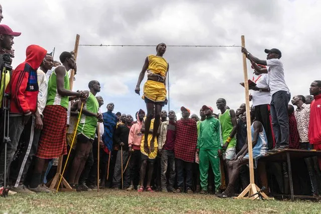 A participant from Rombo village participates in the high jump during the Maasai Olympics in Kimana district, on December 10, 2022, a sports event first held in 2012, in the Amboseli-Tsavo ecosystem. Usually the event is held every second year, but due to the pandemic the event is 2020 was cancelled, so this years event was the first one in four years. Beginning in August 2022, the four competing warrior villages of Eselengei, Kuku, Mbirikani, and Rombo have engaged in local and regional competitions, culminating in the main event. The sports programme of six track-and-field events is based on traditional warrior skills. Running 200 meters, 800 metres and 5,000 meters, spear throwing, rongo (club) throwing into a windsock, high jump, and 1500 and 100 meters running for girls. There is a monetary pize for first, second and third, and the winning village is also awarded a bull. (Photo by Fredrik Lerneryd/AFP Photo)