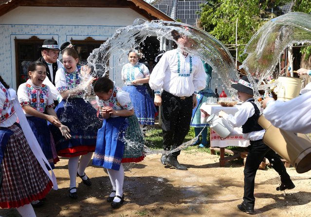 Young girls dressed in traditional clothes react as men throw water at them during a traditional Easter celebration in Csomor, Hungary, on April 21, 2025. (Photo by Bernadett Szabo/Reuters)