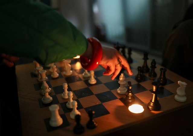 A young woman plays chess under candlelight at Knight Club, a diverse chess club growing to almost a thousand members within a year, based at Fleet Studios, in London, Britain, on June 3, 2025. (Photo by Isabel Infantes/Reuters)