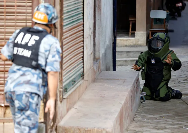 A member of the bomb disposal team gestures as he works to defuse an improvised explosive device planted outside a school in Kathmandu, Nepal September 20, 2016. (Photo by Navesh Chitrakar/Reuters)