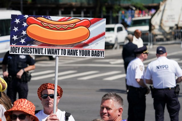 A man holds a sign on the day of the 2025 Nathan's Famous International Hot Dog Eating Contest, at Coney Island, Brooklyn in New York City on July 4, 2025. (Photo by David 'Dee' Delgado/Reuters)