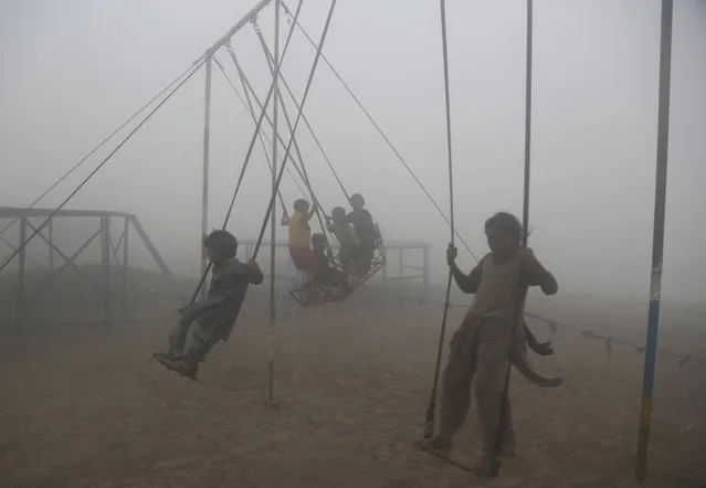 Children ride swings in a playground surrounded by smog in Lahore, Pakistan, Saturday, November 11, 2017. Smog has enveloped much of Pakistan, causing highway accidents and respiratory problems, and forcing many residents to stay home, officials said. (Photo by K.M. Chaudary/AP Photo)