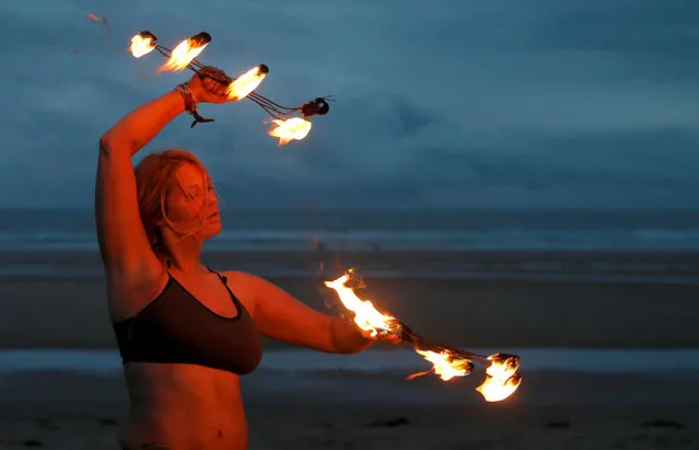 A participants in the annual North East Skinny Dip performs a fire display at Druridge Bay, Britain, September 25, 2016. About 500 people swam naked in the North Sea in aid of charity. (Photo by Russell Cheyne/Reuters)