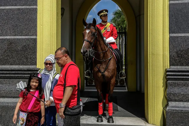 A picture made available 26 September 2016 shows Muslim tourists from Indonesia posing with Malaysia's guard-of-honor at the entrance of the National Palace in Kuala Lumpur, Malaysia, 24 September 2016. South-east Asian nations are cashing in on increasing earnings in the tourism sector from Islamic travelers, and 'Halal Tourism' is reported to be among the fastest growing travel groups. Among other things on offer to Muslim travelers is halal food permitted by Islam, available in specially dedicated restaurants and shops, with no alcohol, and accommodation enabling suitable places for prayer, male and female segregation such as women-only swimming pools and private beaches, conservative uniforms for hotel serving staff, and copies of the Koran in rooms. United Nations World Tourism Day celebrations will be observed on 27 September 2016. (Photo by Ahmad Yusni/EPA)