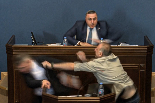 This photo taken from video released by Georgian Parliament on Monday, April 15, 2024, shows the leader of the ruling Georgian Dream party's group in parliament, Mamuka Mdinaradze, left, being punched in the face by opposition MP Alexander Elisashvili while speaking in Tbilisi, Georgia. That then sparked a wider fight between several other lawmakers. Georgian Dream, the governing party in the country of Georgia, said earlier this month that it would resubmit a draft law calling for media and non-commercial organizations to register as being under foreign influence if they receive more than 20% of their budget from abroad. (Photo by Georgian Parliament via AP Photo)
