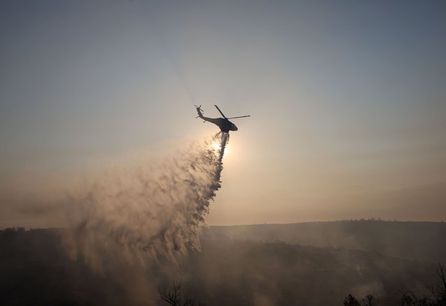 A firefighting helicopter drops water to extinguish fire at the area of Souni near Limassol, Cyprus on July 24, 2025. (Photo by Yiannis Kourtoglou/Reuters)