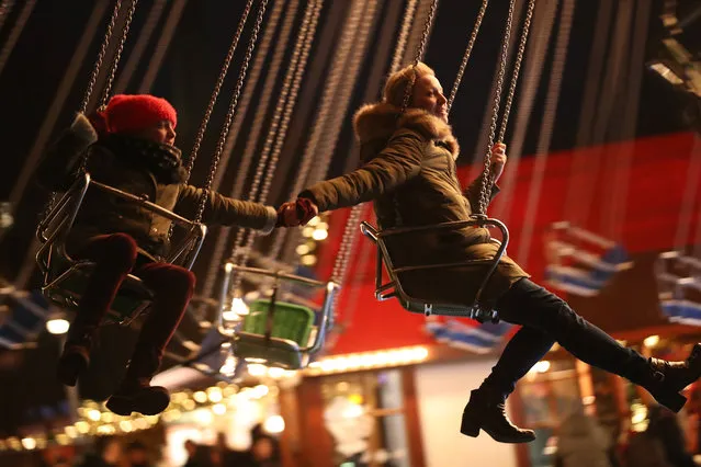 Greta, 9, and her mother hold hands as they enjoy a swing ride at the annual Christmas market at Alexanderplatz on November 28, 2017 in Berlin, Germany. Christmas markets are opening across Germany this week in a tradition that also attracts millions of foreign tourists. (Photo by Sean Gallup/Getty Images)