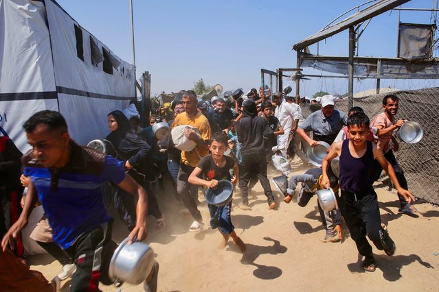 Palestinians rush to queue in line at a charity kitchen in the Mawasi area of Khan Yunis in the southern Gaza Strip on July 22, 2025. The head of Gaza's largest hospital said 21 children have died due to malnutrition and starvation in the Palestinian territory in the past three days, amid a devastating assault by Israeli forces. (Photo by AFP Photo/Stringer)