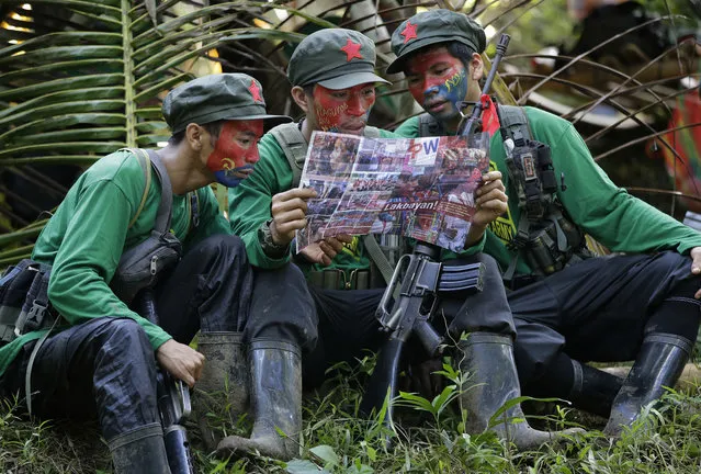 In this November 23, 2016, file photo, members of the New People's Army communist rebels with face painted to conceal their identities, reads a local paper at their guerrilla encampment tucked in the harsh wilderness of the Sierra Madre mountains southeast of Manila, Philippines. Justice officials have asked a court to formally designate the Communist Party of the Philippines and its armed wing, the New People's Army, as terrorist groups in a move that could further damage chances of a resumption of stalled peace talks. (Photo by Aaron Favila/AP Photo)
