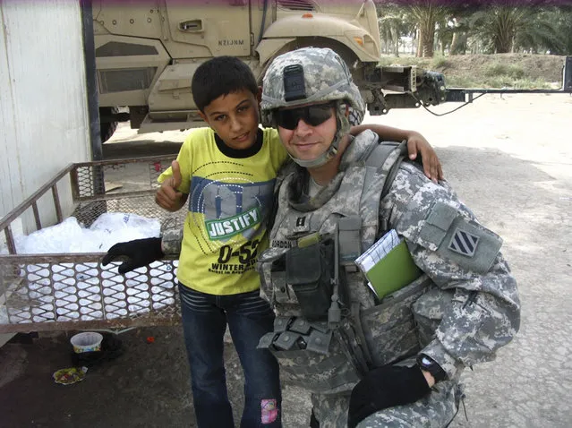 In this undated photo provided by Capt. Nolan Gordon, an Iraqi youngster gathers for a photo with former Army football player Capt. Nolan Gordon in Diyarha Iraq. Like most of the men who played in the 2001 Army-Navy game, Gordon went on to fight in Iraq or Afghanistan – or both – during the 10 years that followed the most deadly terrorist attack on U.S. (Photo by Courtesy Capt. Nolan Gordon/AP Photo)