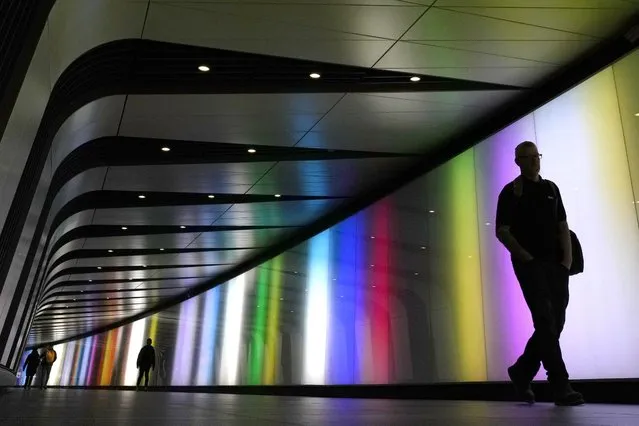 People are silhoueted as they walk through a connecting tunnel in an Underground station in London, Tuesday, April 4, 2023. (Photo by Kirsty Wigglesworth/AP Photo)