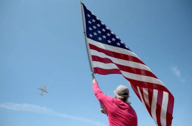 Dan Ray waves an American flag as plane carrying former U.S. President Donald Trump takes off from the Palm Beach International Airport, after Donald Trump was indicted by a Manhattan grand jury following a probe into hush money paid to p*rn star Stormy Daniels, in Palm Beach, Florida, U.S., April 3, 2023. (Photo by Ricardo Arduengo/Reuters)