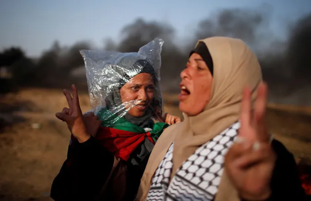 A female demonstrator wears a plastic bag to protect herself from tear gas as another gestures during a protest where Palestinians demand the right to return to their homeland, at the Israel-Gaza border, east of Gaza City May 18, 2018. (Photo by Mohammed Salem/Reuters)