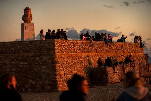 People look at the sunset at a beach at the city of Cadiz in Andalucia, Southern Spain, Sunday, January 3, 2021. (Photo by Emilio Morenatti/AP Photo)