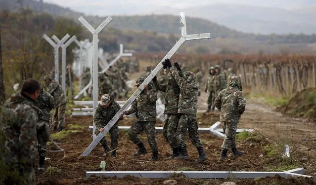 Macedonian soldiers erect a metal fence on the border with Greece, near Gevgelija, Macedonia, November 28, 2015. Soldiers drove metal poles around 3 metres high into the cold, muddy ground, building a barrier similar to that erected by Hungary on its southern border to keep out the hundreds of thousands of migrants who have crossed the Balkans this year. (Photo by Stoyan Nenov/Reuters)