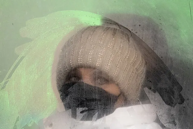 A woman wearing a face mask to help protect herself from the coronavirus looks from a fogged bus window in Ivano-Frankivsk, Western Ukraine, Friday, January 8, 2021. The country of 42 million is recording about 9,000 new COVID-19 infections a day; more than 19,500 people have died. Ukraine imposes a wide-ranging lockdown beginning Friday, closing schools and entertainment venues and restaurant table service through Jan. 25. (Photo by Evgeniy Maloletka/AP Photo)
