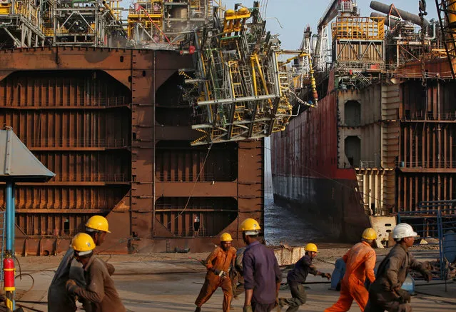 Workers run away as a part of a decommissioned ship falls as it is being dismantled at the Alang shipyard in Gujarat, India, May 28, 2018. (Photo by Amit Dave/Reuters)