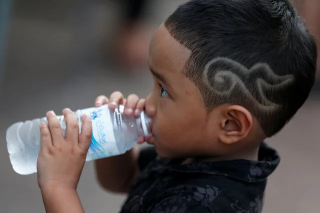 A boy with a haircut symbolising the number 9, which stands for the late King Bhumibol Adulyadej, also known as King Rama IX, as he drinks water outside the Grand Palace in Bangkok,Thailand October 20, 2016. (Photo by Chaiwat Subprasom/Reuters)