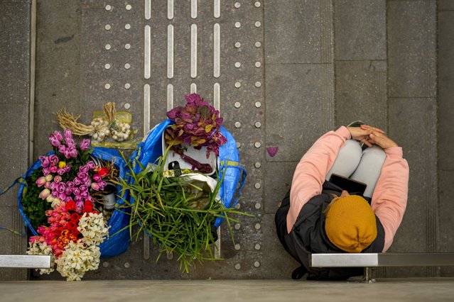 A woman selling flowers and vegetables waits for customers at the entrance of a subway station, in Bucharest, Romania, Wednesday, April 16, 2025. (Photo by Vadim Ghirda/AP Photo)