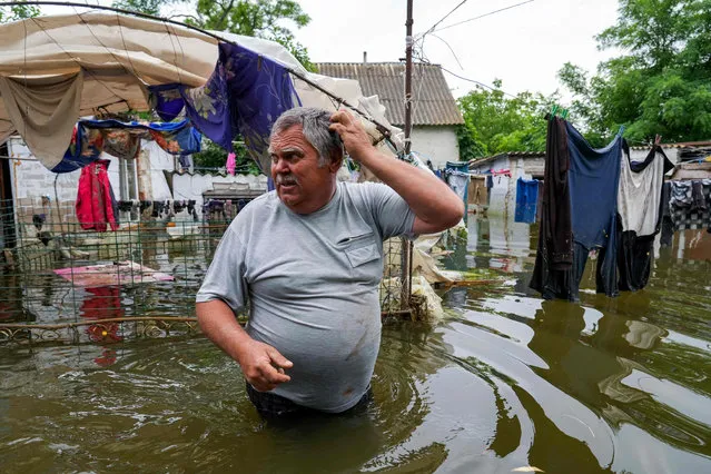 A local resident walks in flooded yard of his house in Afanasiyivka, Mykolayiv region on June 10, 2023, following damages sustained at Kakhovka hydroelectric power plant dam. (Photo by Aleksey Filippov/AFP Photo)