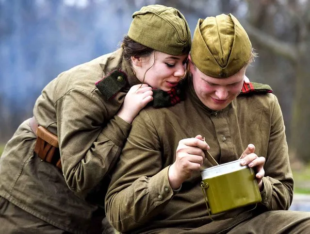 Hayley Ruyle watches her boyfriend Kyle Phillips of Greenfield, Ill., eat his lunch as the two re-enactors dressed as Russian soldiers take a break from battles during a World War II re-enactment at Sommer Park in Peoria, Ill., Saturday, December 12, 2015. (Photo by Ron Johnson/Journal Star via AP Photo)