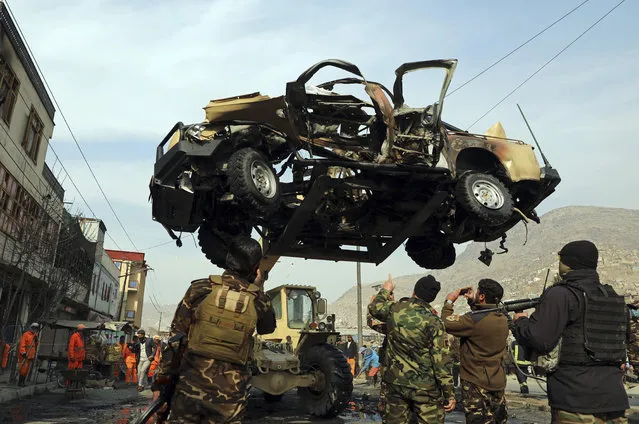 Afghan security personnel remove a damaged vehicle after a bomb attack in Kabul, Afghanistan, Monday, February 1, 2021. A sticky bomb attached to an army vehicle exploded Monday in the capital, Kabul, killing and wounding several people. (Photo by Rahmat Gul/AP Photo)