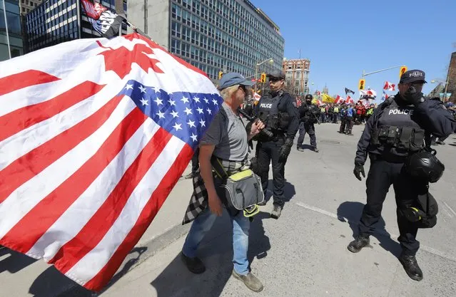 A protester walks past police at a demonstration, part of a convoy-style protest participants are calling “Rolling Thunder” in Ottawa, Ontario, on Saturday, April 30, 2022. (Photo by Patrick Doyle/The Canadian Press via AP Photo)