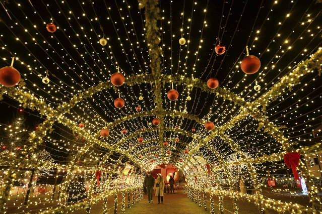 Visitors walk under Christmas decorations at the local Catholic church on the eve of the Christmas celebrations in the village of Petrushan, near the town of Gjakova, Kosovo on December 22, 2023. (Photo by Armend Nimani/AFP Photo)