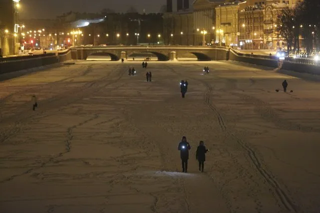 People shine their cellphone flashlights in support of jailed opposition leader Alexei Navalny and his wife Yulia Navalnaya walking on the ice of Neva River in St. Petersburg, Russia, Sunday, February 14, 2021. When the team of jailed Russia opposition leader Alexei Navalny announced a protest in a new format, urging people to come out to their residential courtyards on Sunday and shine their cellphone flashlights, many responded with jokes and skepticism. After two weekends of nationwide demonstrations, the new protest format looked to some like a retreat. But not to Russian authorities, who moved vigorously to extinguish the illuminated protests planned for Sunday. (Photo by Valentin Egorshin/AP Photo)