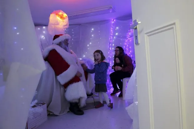 Five-year-old Leila Matheson reacts as she meets actor John Field, dressed as Santa Claus, at a Christmas grotto at a dental practice in north London, Britain, December 12, 2015. When Father Christmas is not at home with the reindeer preparing for his big sleigh-ride, he likes to play practical jokes on the children who visit him asking for presents.Â Field, 66, a former teacher turned actor, has taken on the role of Santa for the past 12 years. “I'm playing a part but it is one of the most truthful parts I can play”, he says. (Photo by Stefan Wermuth/Reuters)