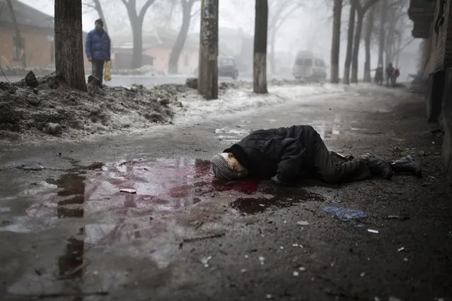 A body of a civilian killed when a mortar shell landed near a bus stop, lies on the ground in Donetsk, eastern Ukraine, Friday, January 30, 2015. (Photo by Vadim Braydov/AP Photo)