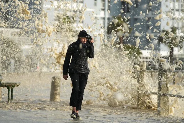 A woman runs through a sea foam, as a seasonal cold front moved over the Cape Peninsula, following a week of severe weather and flooding in Cape Town, South Africa on June 19, 2023. (Photo by Nic Bothma/Reuters)
