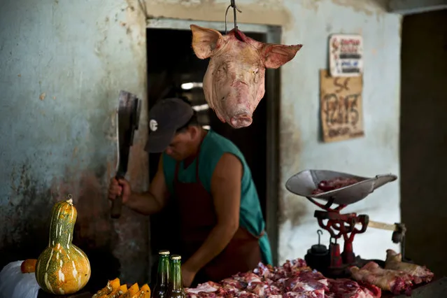 In this July 25, 2018 photo, a pig head hangs for sale at a butcher shop in Guantanamo, Cuba, near the U.S. Guantanamo Bay naval base. Pork is the most accessible meat in Cuba, where the pig even has its own song: “El Puerco Mamífero Nacional”, or “National Mammal Pork”, by the Buena Fe band. (Photo by Ramon Espinosa/AP Photo)