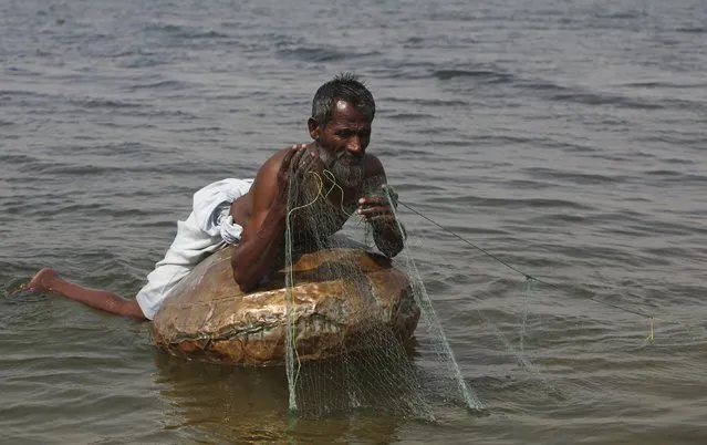 A man uses a floating pitcher to balance on as he sets up a net at Keenjhar Lake, near Thatta, February 22, 2015. (Photo by Akhtar Soomro/Reuters)