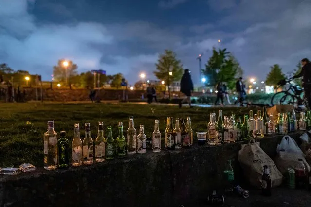 Empty bottles are seen lined up as people gather after midnight on the bank of the Vistula river to celebrate the easing of the coronavirus restrictions as restaurant terraces re-open and outdoor mask obligation was lifted on May 15, 2021 in Warsaw, Poland. (Photo by Wojtek Radwanski/AFP Photo)
