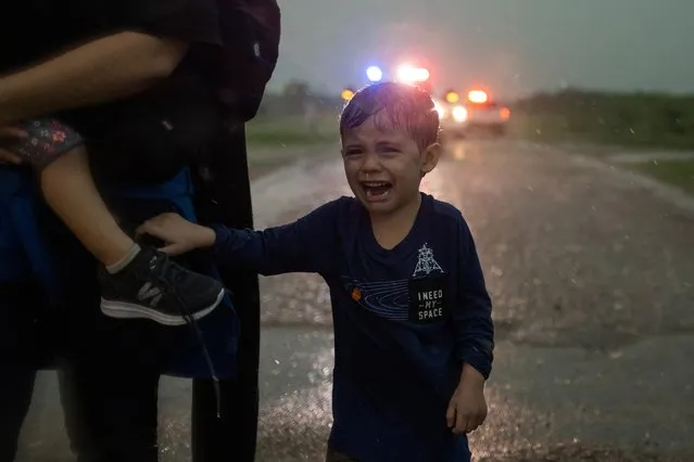 Dylan, a four year old asylum-seeking migrant boy from Honduras, holds onto his mother as they look for cover from heavy rainfall after crossing the Rio Grande river into the United States from Mexico in La Joya, Texas, U.S., May 19, 2021. (Photo by Adrees Latif/Reuters)