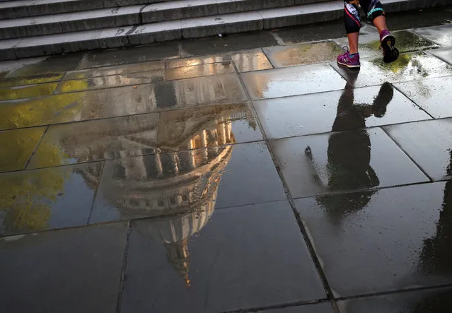 A woman jogs past a reflection of St Paul's Cathedral on the wet pavement on a sunny morning in London, Britain, May 8, 2018. (Photo by Hannah McKay/Reuters)