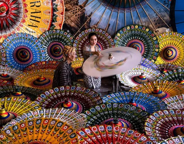 Artists are surrounded by swirling colour as they put the finishing touches to traditional Indonesian umbrellas in Klaten, Java early September 2023.The umbrellas are used for religious activities, traditional ceremonies or decoration. (Photo by Syamsul Huda Yudha/Solent News)