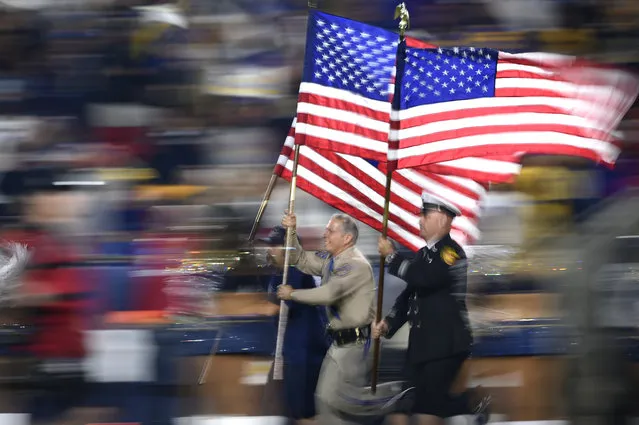 Fire and and law enforcement first responders run with United States flags as they lead players out of the tunnel before an NFL football game between the Los Angeles Rams and the Kansas City Chiefs, Monday, November 19, 2018, in Los Angeles. (Photo by Kelvin Kuo/AP Photo)