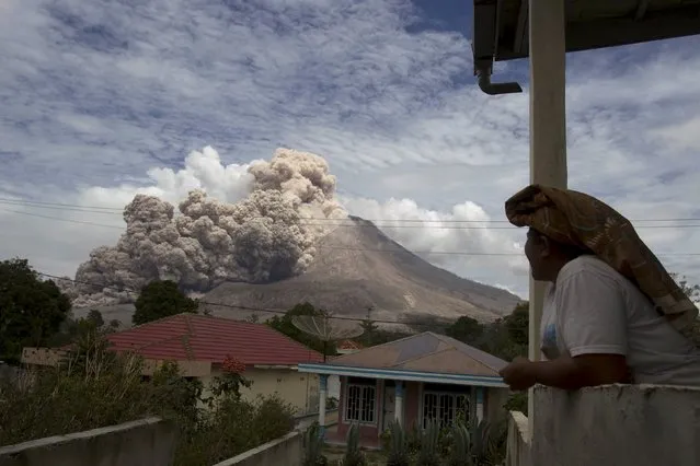 A villager watches as Mount Sinabung volcano erupts, in Kuta Tengah village, Karo Regency in Indonesia's North Sumatra April 1, 2015. The Indonesian volcano was dormant for 400 years before erupting in 2010. (Photo by Y. T. Haryono/Reuters)