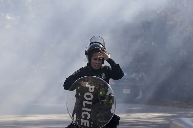 A police officer runs out of a cloud of gas during a demonstration in opposition to a new police training center, Monday, November 13, 2023, in Atlanta. (Photo by Mike Stewart/AP Photo)