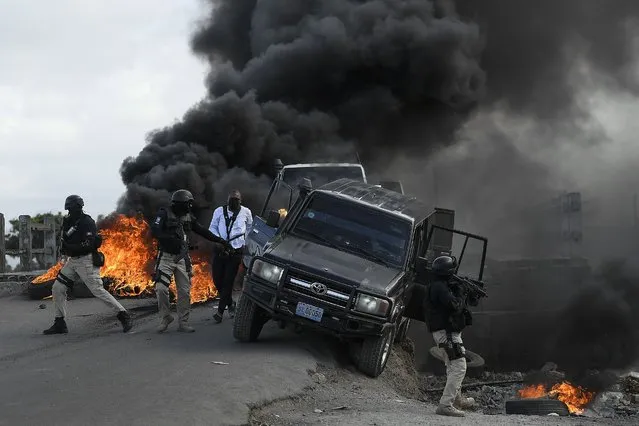 Police abandon their vehicle during a demonstration that turned violent in which protesters demanded justice for the assassinated President Jovenel Moise  in Cap-Haitien, Haiti, Thursday, July 22, 2021. Demonstrations after a memorial service for Moise turned violent on Thursday afternoon with protesters shooting into the air, throwing rocks and overturning heavy concrete barricades next to the seashore as businesses closed and people took cover. (Photo by Matias Delacroix/AP Photo)