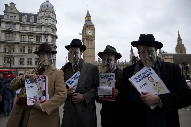 Representatives of Leave.EU, an anti-EU membership campaign group, pose for photographs wearing masks to represent British Prime Minister David Cameron dressed as a 1940s spiv, a slang word for a type of shady character, backdropped by the Houses of Parliament and Big Ben in London, Friday, February 19, 2016. Cameron forged ahead at tougher-than-expected talks with European partners Friday after meetings through the night failed to make much progress on his demands for a less intrusive European Union. (Photo by Matt Dunham/AP Photo)